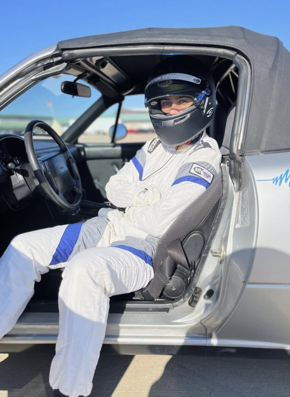 A student suited up and belted into the driver's seat at Motorsport Ranch, helmet on, before going out on track