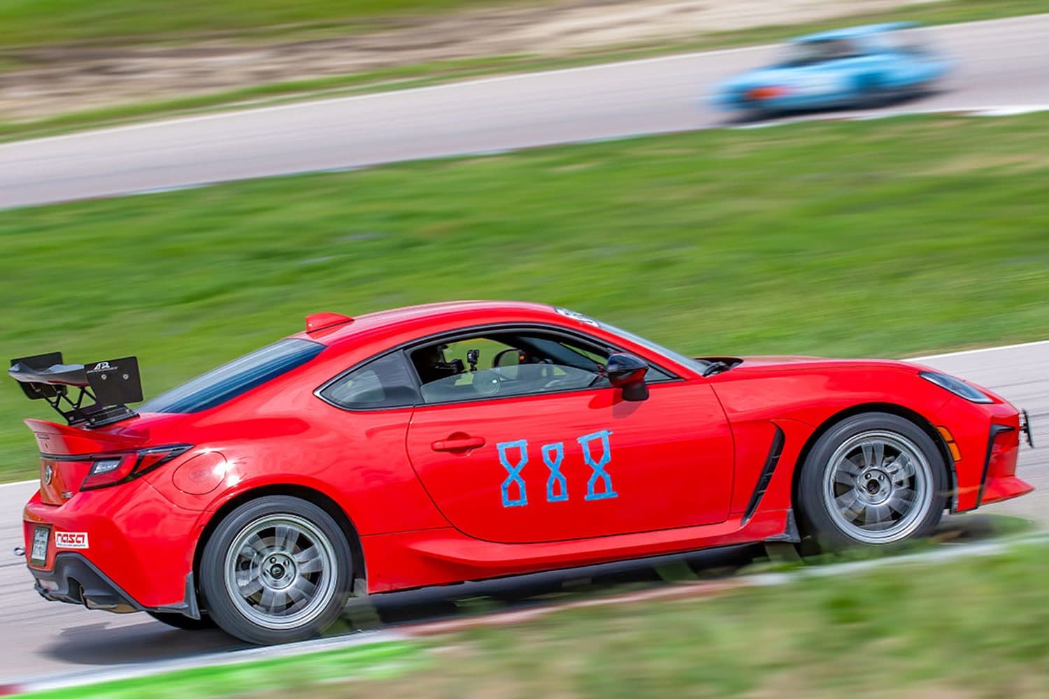 A Toyota GR86 at speed on track at a NASA event — a road-legal sports car, not a purpose-built race car