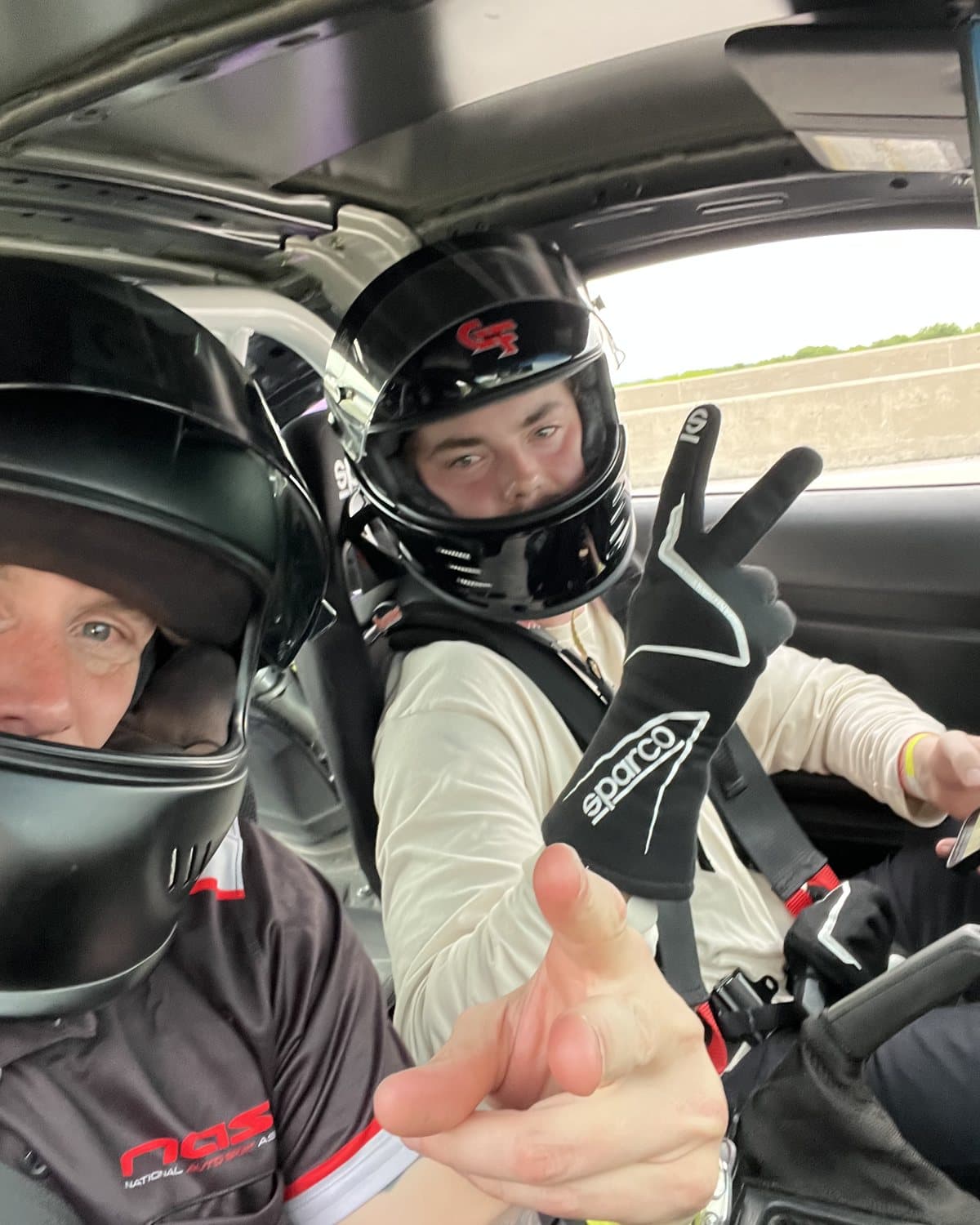 Jon-Eric coaching a student from the passenger seat on track at Motorsport Ranch Cresson, both in helmets